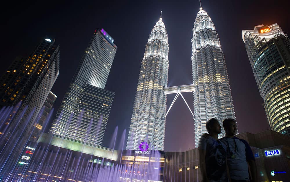 Tourists has their souvenir photograph taken against the Petronas Twin Towers in Kuala Lumpur, Malaysia. Two airplane catastrophes put Malaysia on the map in a bad way in 2014. 