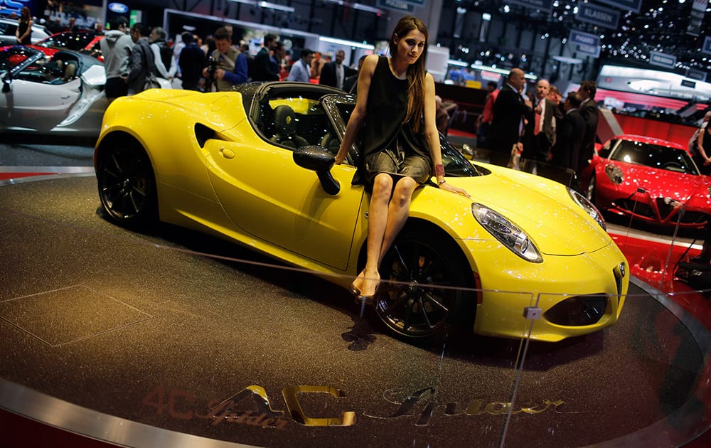 A model sits on the Alfa Romeo 4C Spider during the first press day of the Geneva International Motor Show in Geneva, Switzerland.
