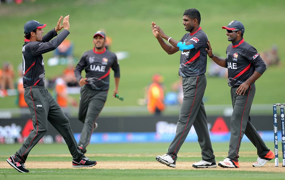 United Arab Emirates K. Karate, right, and Rohan Mustafa, left, congratulate teammate Manjula Guruge after taking the wicket of Pakistan's Nasir Jamshed during their Cricket World Cup Pool B match in Napier, New Zealand.