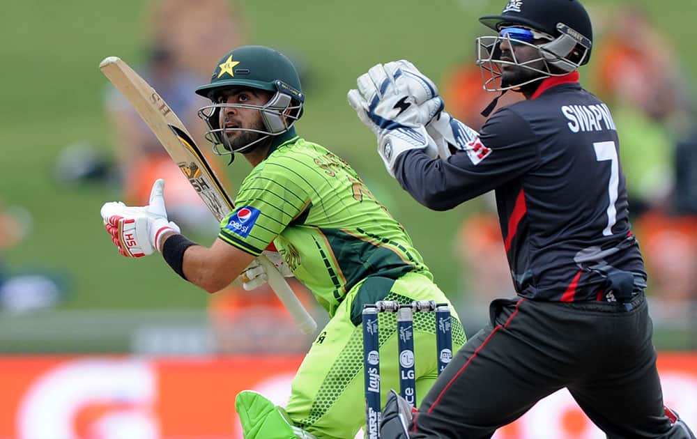 Pakistan batsman Ahmad Shahzad, left, plays a shot as United Arab Emirates wicketkeeper Swapnil Patil watches during their Cricket World Cup Pool B match in Napier, New Zealand.