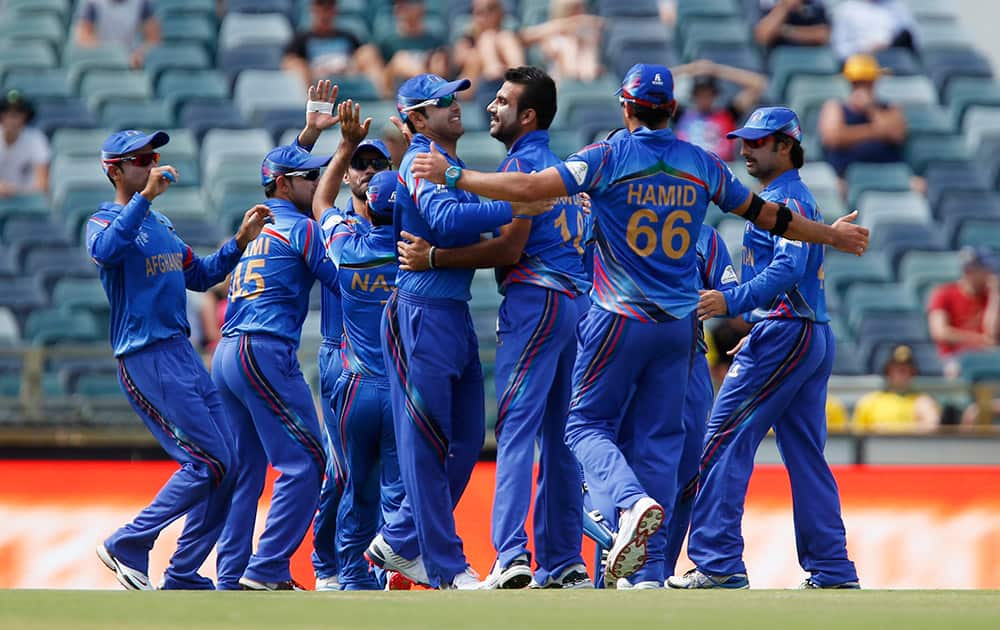 Afghanistan’s cricketers rush in to celebrate with teammate Dawlat Zadran for the dismissal of Australia's Aaron Finch during their Cricket World Cup Pool A match in Perth, Australia.