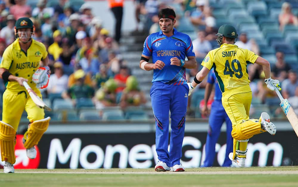 Afghanistan’s Hassan Hamid looks towards the ball, as Australia's Steve Smith and David Warner complete a run during their Cricket World Cup Pool A match in Perth, Australia.