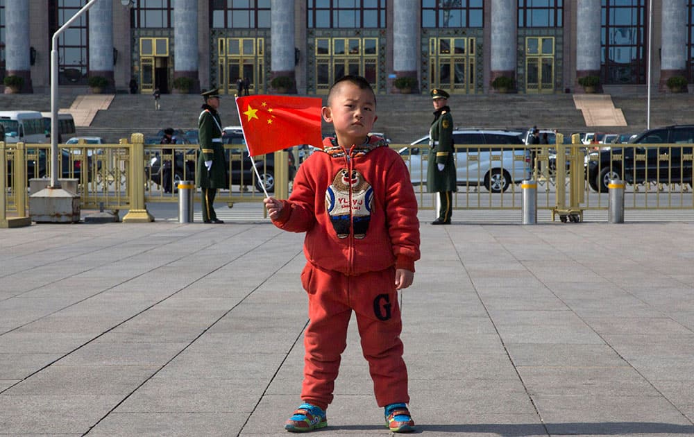 A child holds a Chinese national flag as he poses for photos in front of the Great Hall of the People in Beijing.