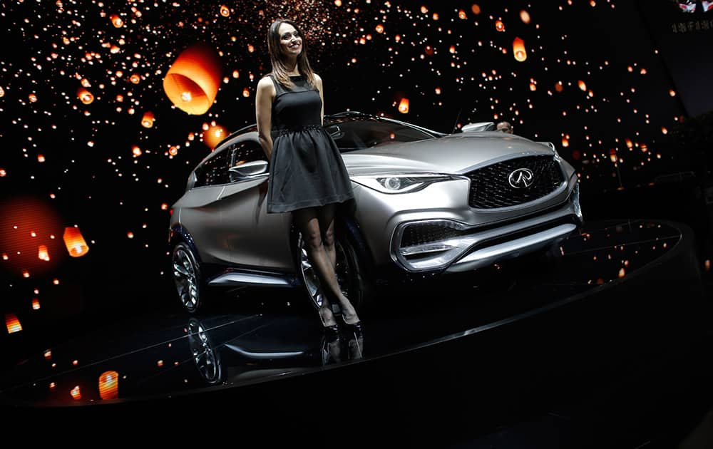 A model poses in front of the QX 30 of Infinity, the luxury vehicle division of Nissan, on the second press day of the Geneva International Motor Show in Geneva, Switzerland. 