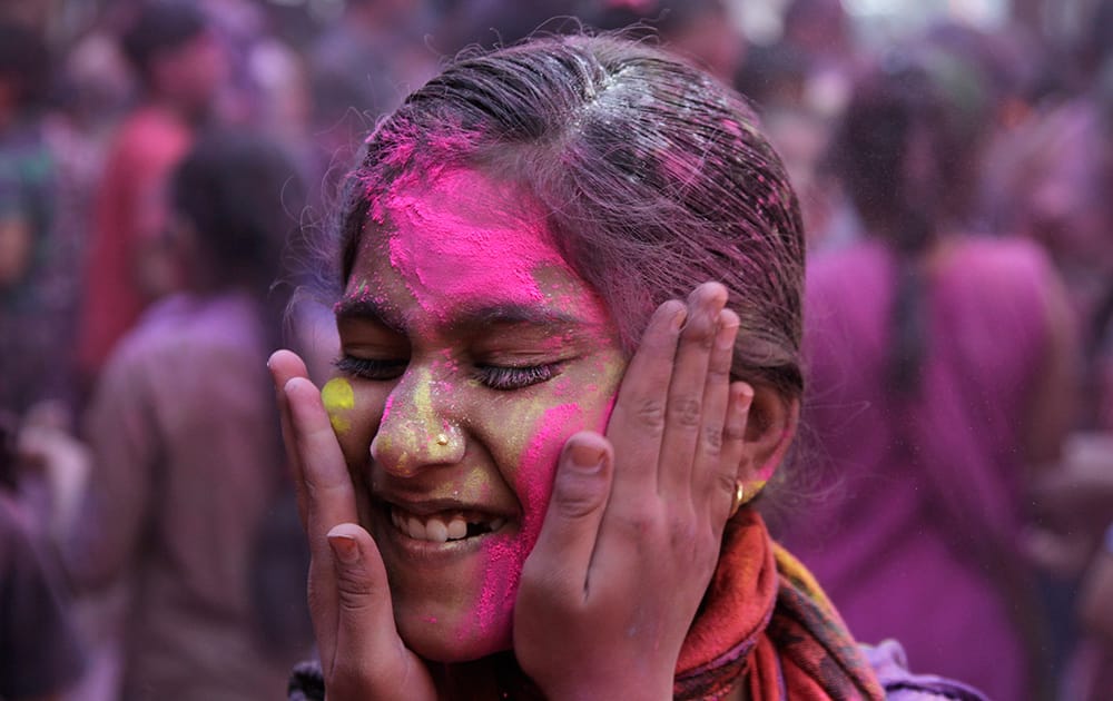 A schoolgirl closes her eyes as another applies color on her face during celebrations marking Holi at a school in Ahmadabad.