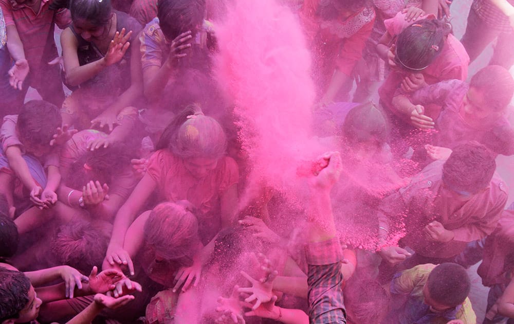 A teacher throws colored powder on school children during celebrations marking Holi, the Hindu festival of colors, at a school in Ahmadabad.