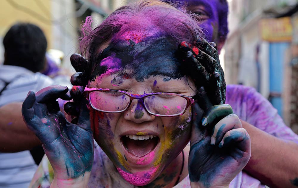 A foreign tourist screams as another puts color on her face during celebrations marking Holi in Kolkata.