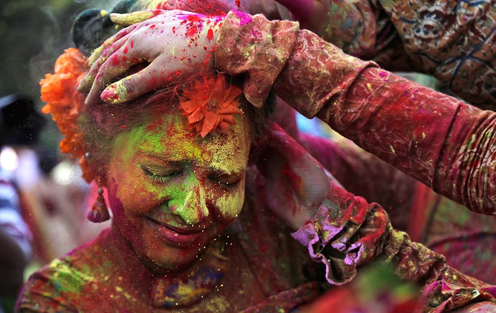 People put colored powder on the face of a girl as they celebrate Holi in Kolkata.