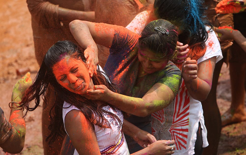 Girls throw colored powder on each other during Holi celebrations in Hyderabad.