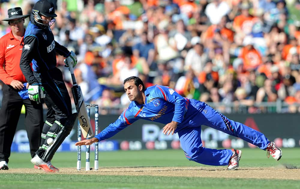 Afghanistan’s Samiullah Shenwari dives to take the ball as New Zealand batsman Martin Guptill moves out of the way during their Cricket World Cup Pool A match in Napier, New Zealand.