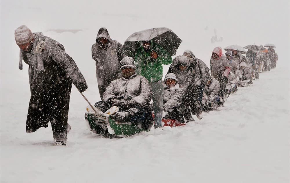 Kashmiri guides pull sleighs carrying tourists after heavy snowfall in in Gulmarg.