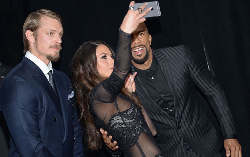 Actors Joel Kinnaman, from left, Genesis Rodriguez and Common take a selfie on the red carpet at the world premiere of 