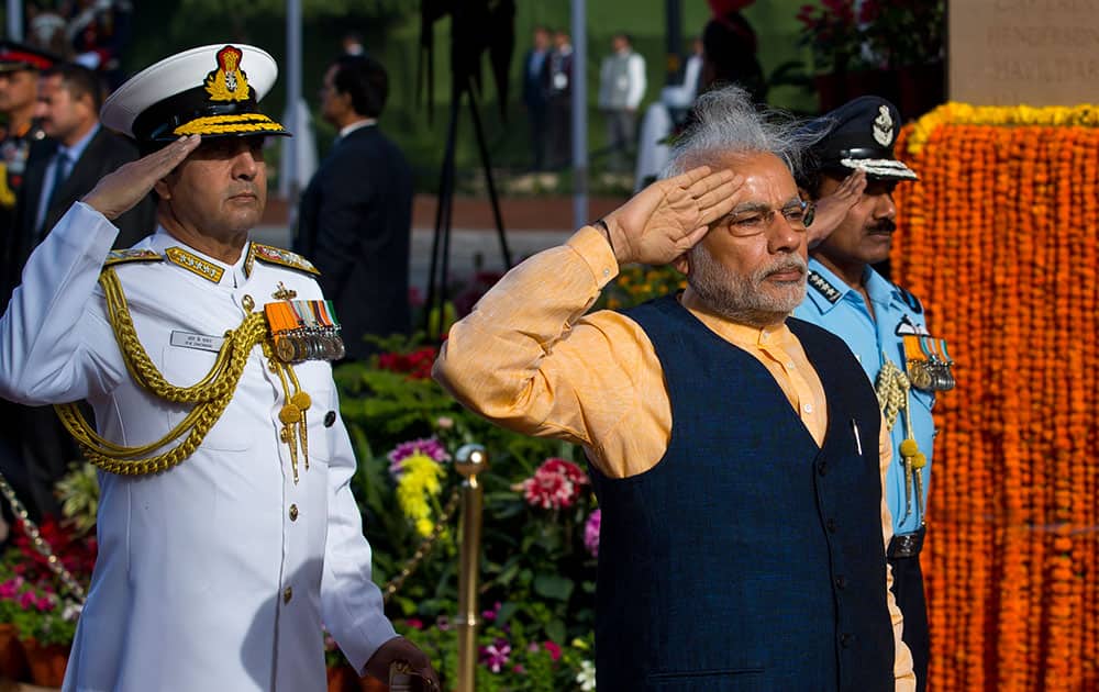Prime Minister Narendra Modi salutes in front of a World War I memorial at India Gate, flanked by Naval chief Admiral R.K. Dhowan, left, and Air Chief Marshal Arup Raha in New Delhi, India.