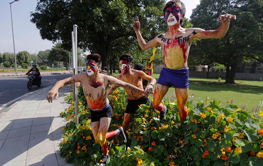 Tibetan exiles, their faces painted in the colors of the Tibetan flag, jump over a flower bed as they make their way towards the Chinese Embassy during a protest in New Delhi, India.