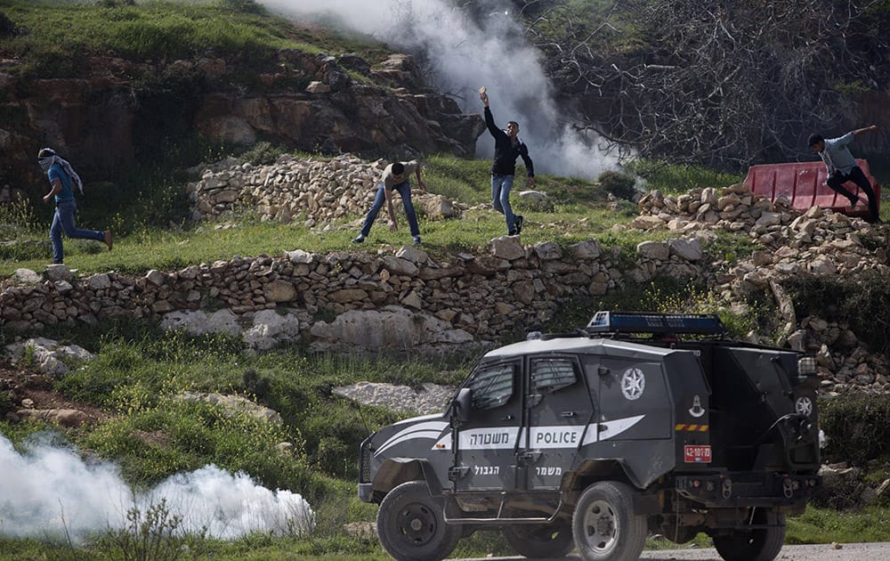 Palestinian protesters throw stones at an Israeli police vehicle during clashes at a protest marking a year since the killing of Saji Darwish, a Palestinian shot by the Israeli army, outside Ofer, an Israeli military prison near the West Bank city of Ramallah.
