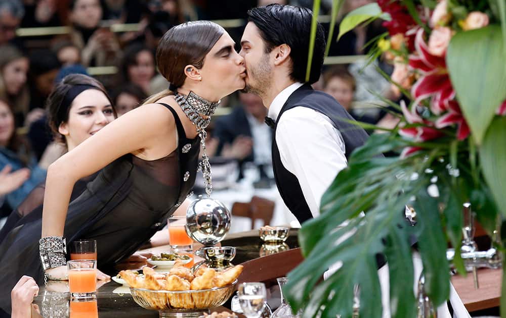 Model Cara Delevingne kisses a waiter as she wears creations for Chanel's ready to wear fall-winter 2015-2016 fashion collection during Paris fashion week.
