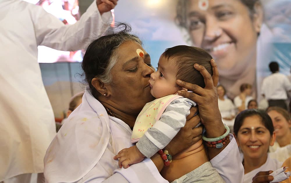 Indian spiritual leader Mata Amritanandamayi kisses to bless a child of a devotee during a prayer meeting in Bangalore.