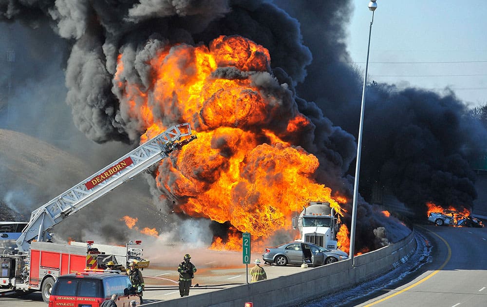 Dearborn, Mich., firefighters watch as a tanker truck, and at least one car, right, burn shutting down a stretch Interstate 94, Dearborn, Mich. Michigan State Police Lt. 