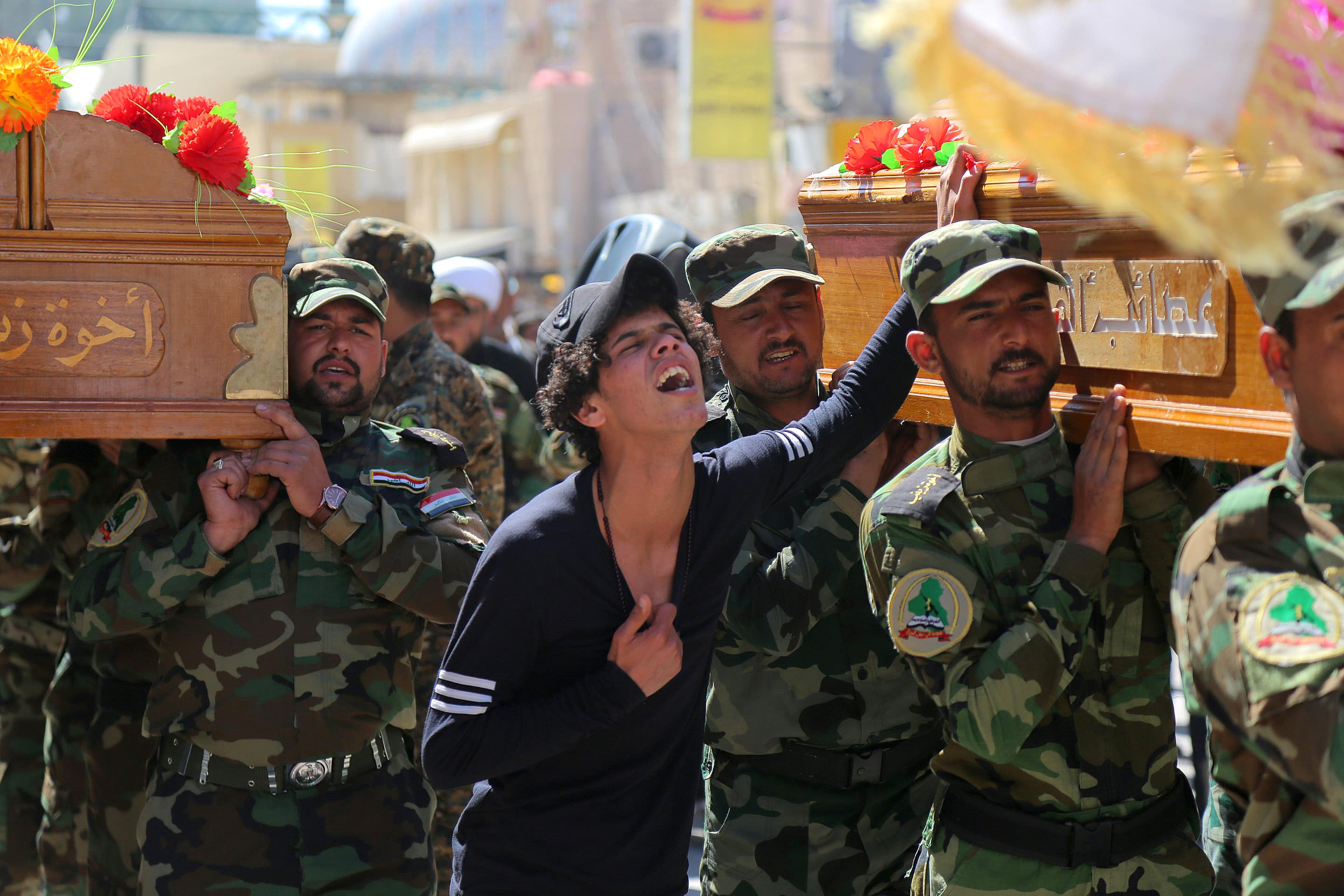 mourners chant slogans against the Islamic State group during the funeral procession of three members of a Shiite group, Asaib Ahl al-Haq, or League of the Righteous, who were killed in Tikrit while fighting Islamic militants, in Najaf, 100 miles (160 kilometers) south of Baghdad, Iraq. 