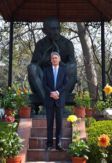 British Foreign Secretary Philip Hammond poses for a photograph in front of a statue of Mahatma Gandhi during a visit to a Gandhi memorial in New Delhi.