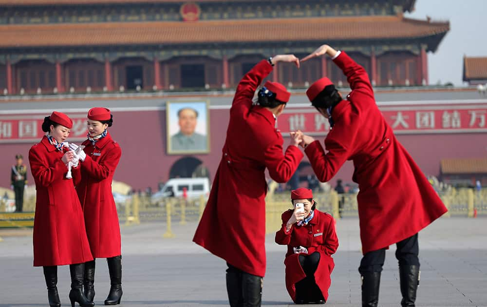 Chinese hostesses, who serve the delegates of the National People's Congress, have souvenir photos taken on Tiananmen Square during a plenary session of the NPC held at the Great Hall of the People in Beijing.