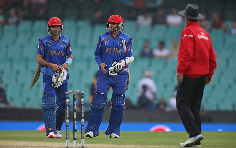 Afghanistan’s Jamal Nasir, center, and Afsar Zazai remove their gloves after Umpire Billy Bowden temporarily called off the match because of rain during the Cricket World Cup pool A match against England in Sydney.