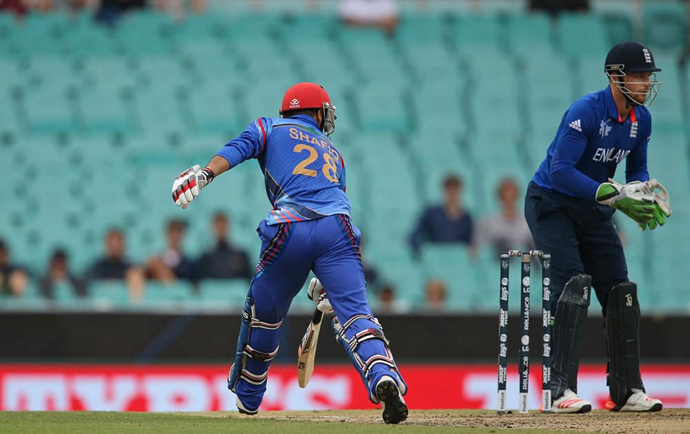 Afghanistan's Shafiqullah takes a run as England's Jos Buttler, right, cups his hands to receive the ball during their Cricket World Cup pool A match in Sydney.