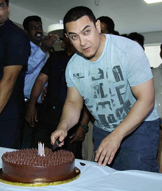 Bollywood actor Aamir Khan cuts a cake to celebrate his 50th birthday at his residence in Mumbai.