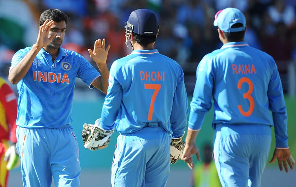 Ravichandran Ashwin, left, is congratulated by teammates MS Dhoni and Suresh Raina, right, after dismissing Zimbabwe batsman Sean Williams during their Cricket World Cup Pool B match in Auckland