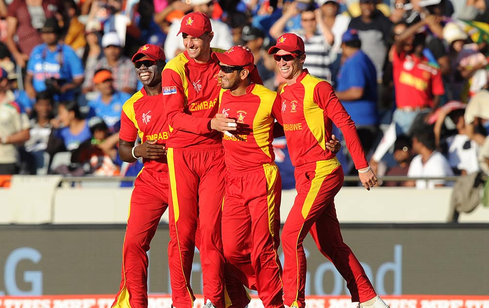 Zimbabwe's Raza Butt, is congratulated by teammates after taking a catch to dismiss India's Rohit Sharma during their Cricket World Cup Pool B match in Auckland, New Zealand.