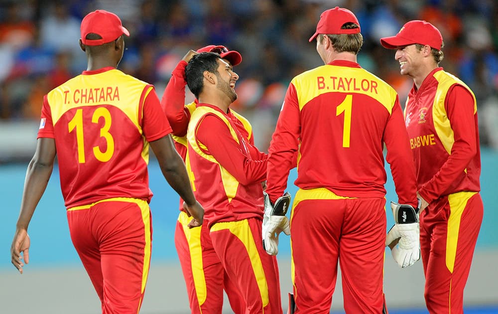 Zimbabwe's Raza Butt, is congratulated by his teammates after dismissing India's Virat Kohli during their Cricket World Cup Pool B match in Auckland.