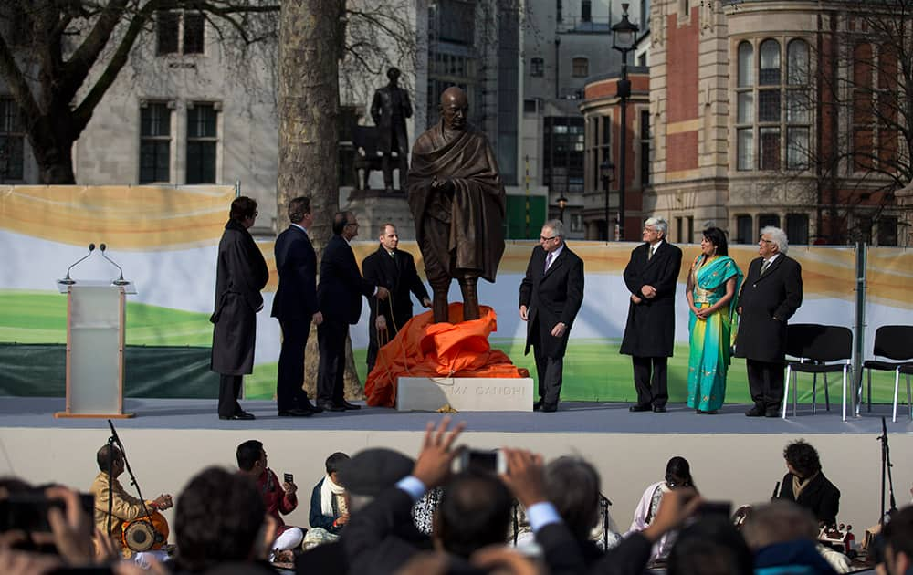 A new statue of Mahatma Gandhi by British sculptor Philip Jackson is unveiled by Finance Minister Arun Jaitley, watched by Amitabh Bachchan, British Prime Minister David Cameron and Gandhi's grandson Gopalkrishna Gandhi, third right, in Parliament Square, London.