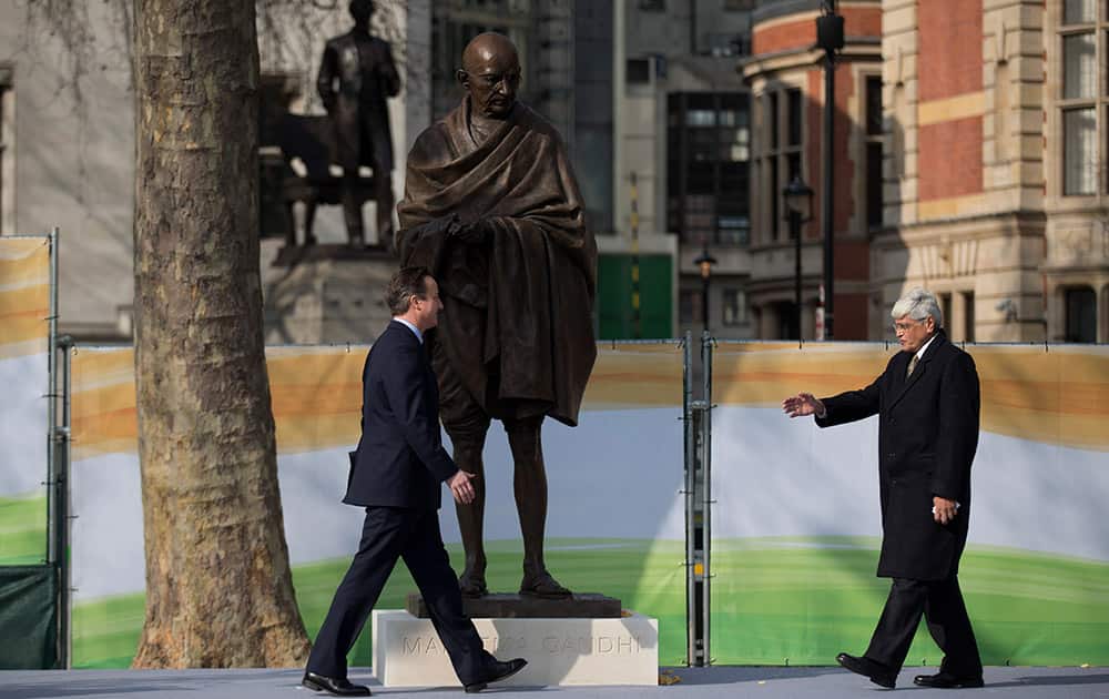 British Prime Minister David Cameron and Gandhi's grandson Gopalkrishna Gandhi walk to shake hands beneath a new statue of Mahatma Gandhi by British sculptor Philip Jackson after it was unveiled in Parliament Square, London.