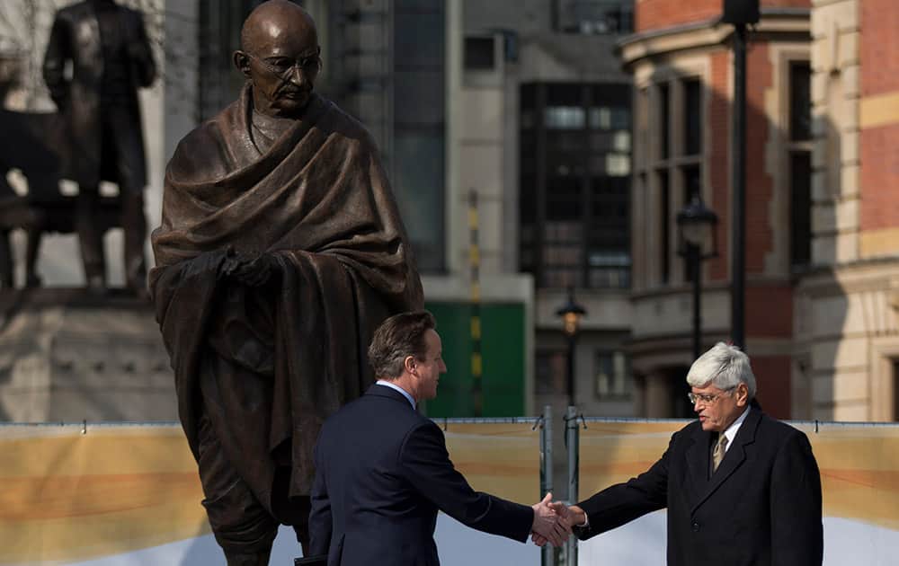 British Prime Minister David Cameron and Gandhi's grandson Gopalkrishna Gandhi shake hands beneath a new statue of Mahatma Gandhi by British sculptor Philip Jackson, after it was unveiled in Parliament Square, London.