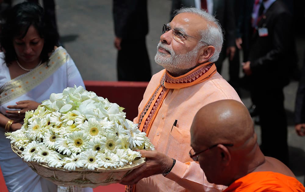 Prime Minister Narendra Modi walks with a tray of flowers to offer at Maha Bodhi Buddhist temple during his visit to Colombo, Sri Lanka.