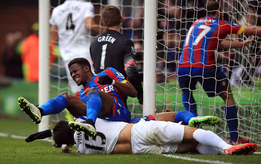 Crystal Palace's Wilfried Zaha collides with the post after scoring against Queens Park Rangers during the English Premier League soccer match at Selhurst Park, London.