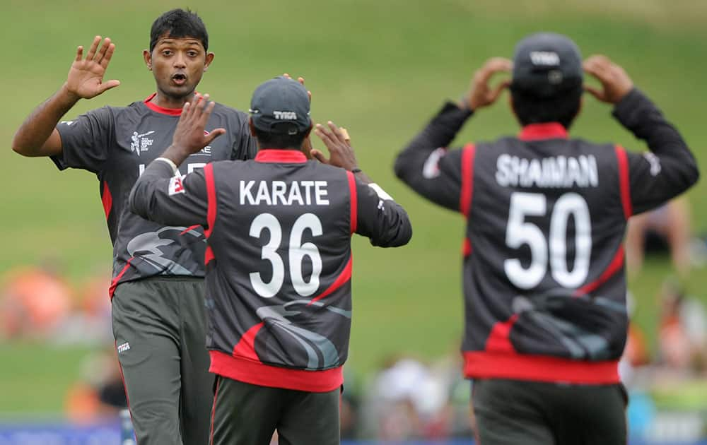 United Arab Emirates bowler Amjad Javed, left, celebrates with teammates K. Karate and Shaiman Anwar, right, after taking the wicket of West Indies batsman Johnson Charles during their Cricket World Cup Pool B match in Napier, New Zealand.