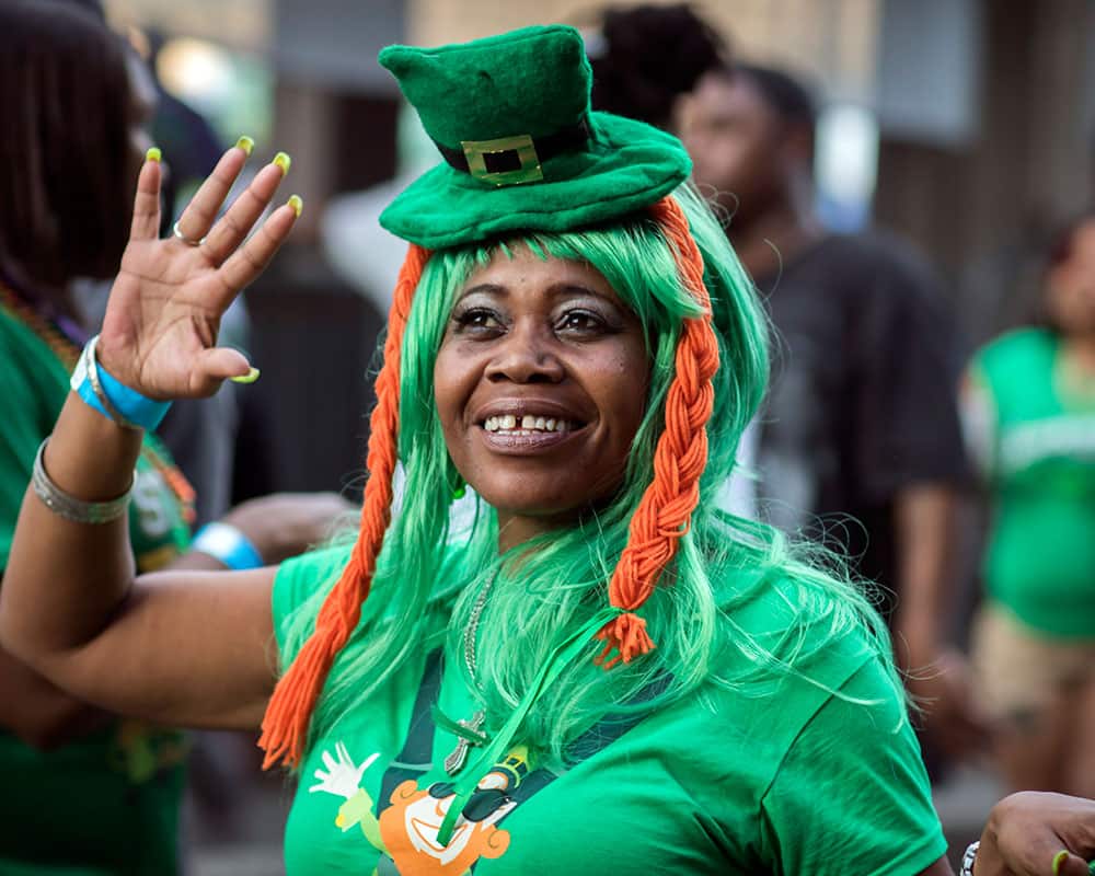 Dressed as a leprechaun Jackie Robinson, of Atlanta, waves to friends as she walking along River Street during the start of a four-day St. Patrick's Day celebration on River Street in Savannah, Ga.