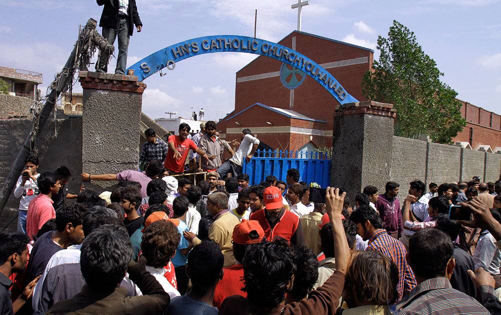 Pakistani Christians and rescue workers gather outside a church damaged from a suicide bombing attack in Lahore, Pakistan.