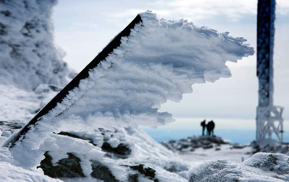 Rime ice extends horizontally from a metal pole at the summit of Mt. Washington, in New Hampshire. Rime ice forms in the direction of the wind driven fog that often blows across the summit at hurricane force.