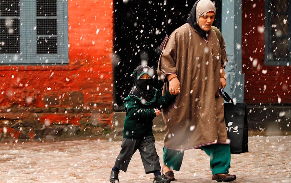 A Kashmiri woman walks with her daughter outside a school as it snows in Srinagar, India.