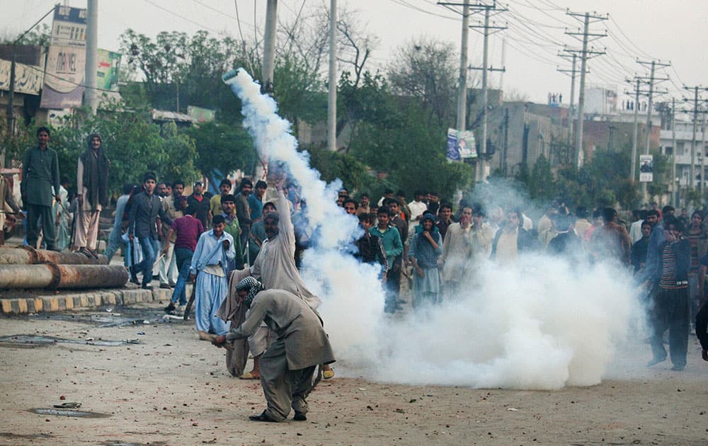 Pakistani protesters take cover during clashes with police, in Lahore.