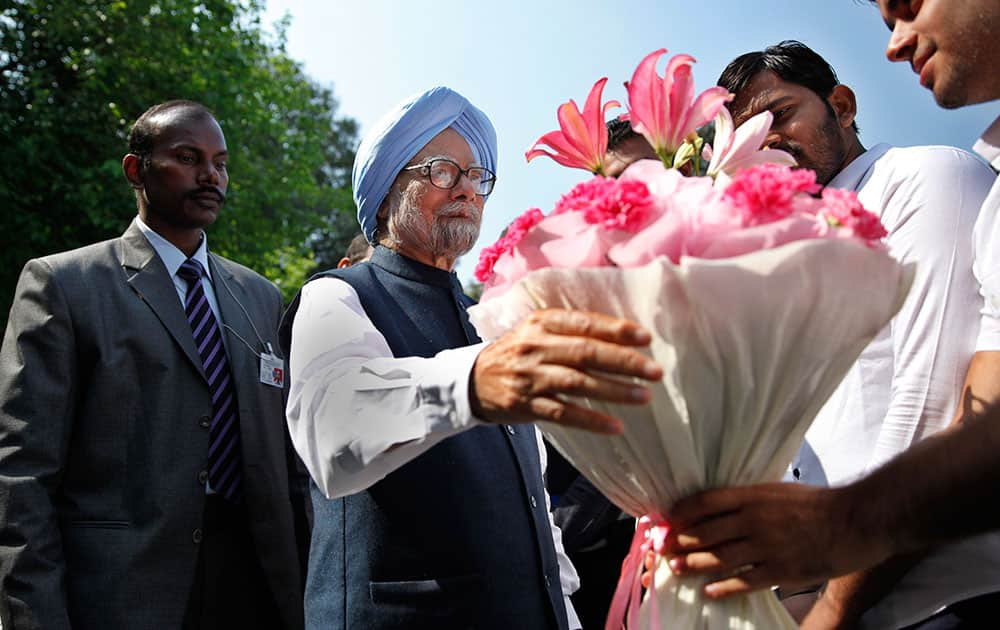 Former Indian prime minister Manmohan Singh, center, receives a bouquet of flowers from the newly elected office bearers of 