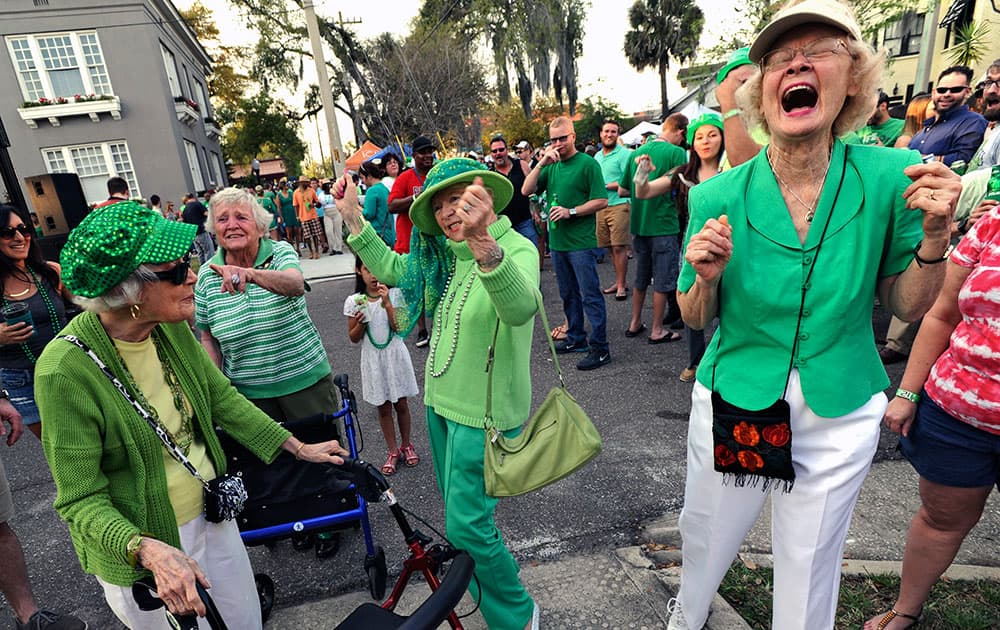 A group of ladies from the Riverside Presbyterian Apartments from left, Virginia Happel, Jackie Ogilvie, Di Tyree and Joyce Hallmark, stop to dance as O'Brothers Irish Pub celebrates St. Patrick's Day with a street party in Jacksonville, Fla.