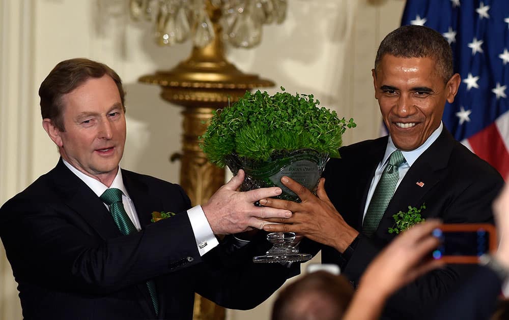 President Barack Obama, right, and Irish Prime Minister Enda Kenny, left, hold up a bowl of shamrocks during a reception in the East Room of the White House in Washington.