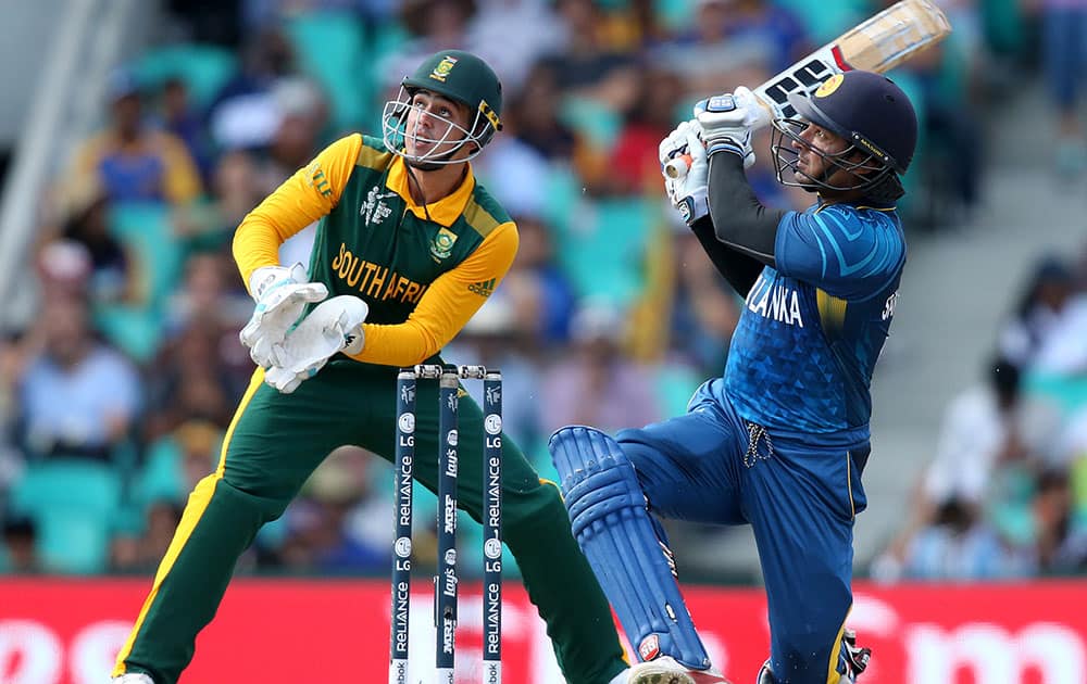 Sri Lanka's Kumar Sangakkara hits the ball to the boundary as South African wicketkeeper Quinton De Kock watches during their Cricket World Cup quarterfinal match in Sydney, Australia.