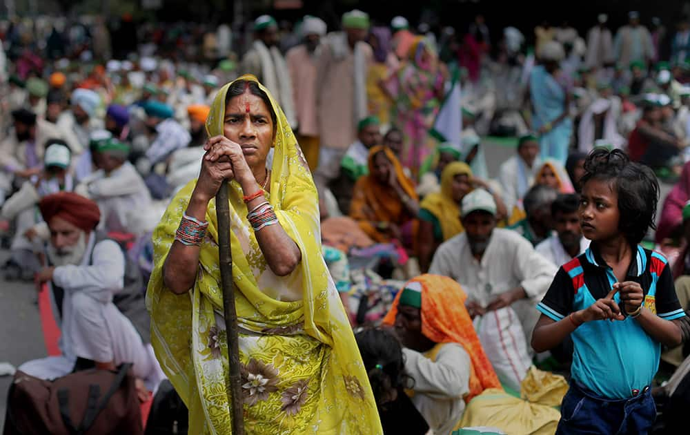 A woman farmer leans on her stick as she attends a huge gathering of farmers near the parliament for a protest against the land acquisition bill, in New Delhi.