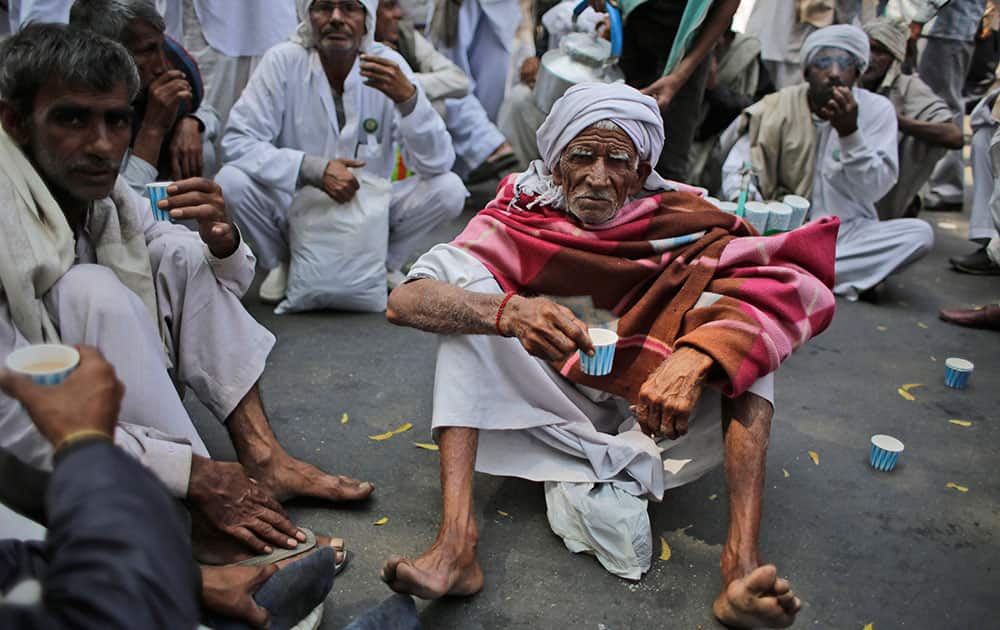 farmers sip tea as they gather near the parliament for a protest against the land acquisition bill, in New Delhi.