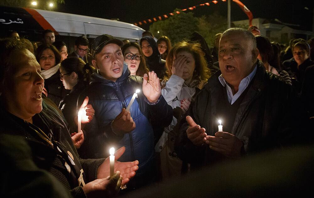 Tunisians holding candles pray at the entrance gate of the National Bardo Museum where scores of people were killed after gunmen staged an attack, Tunisia.