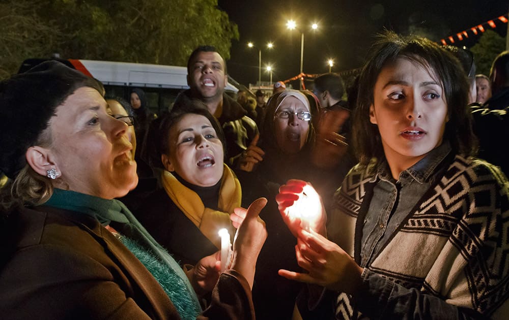 Tunisians holding candles chant pro government slogans outside the National Bardo Museum where scores of people were killed after gunmen staged an attack, Tunisia.